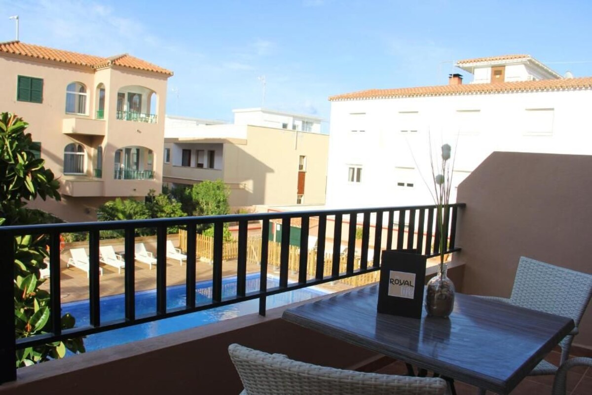 A balcony with a pool view, a table with a vase, and a sign labeled "ROYAL".
