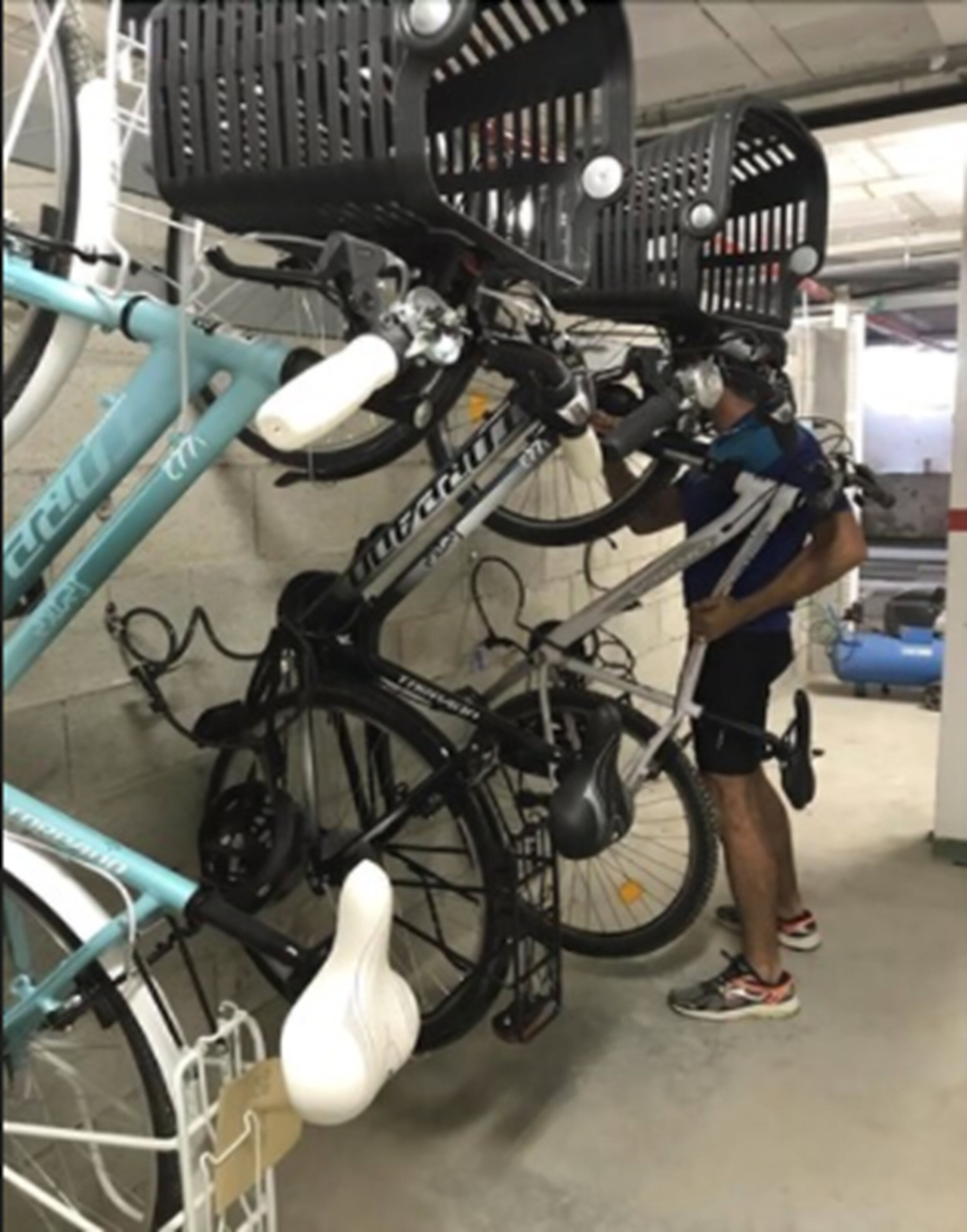 A person standing next to a bicycle in a covered parking area.