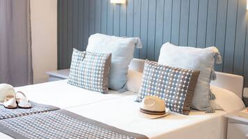 Una cama bien hecha con ropa de cama estampada, una mesita de noche y una lámpara de pared.