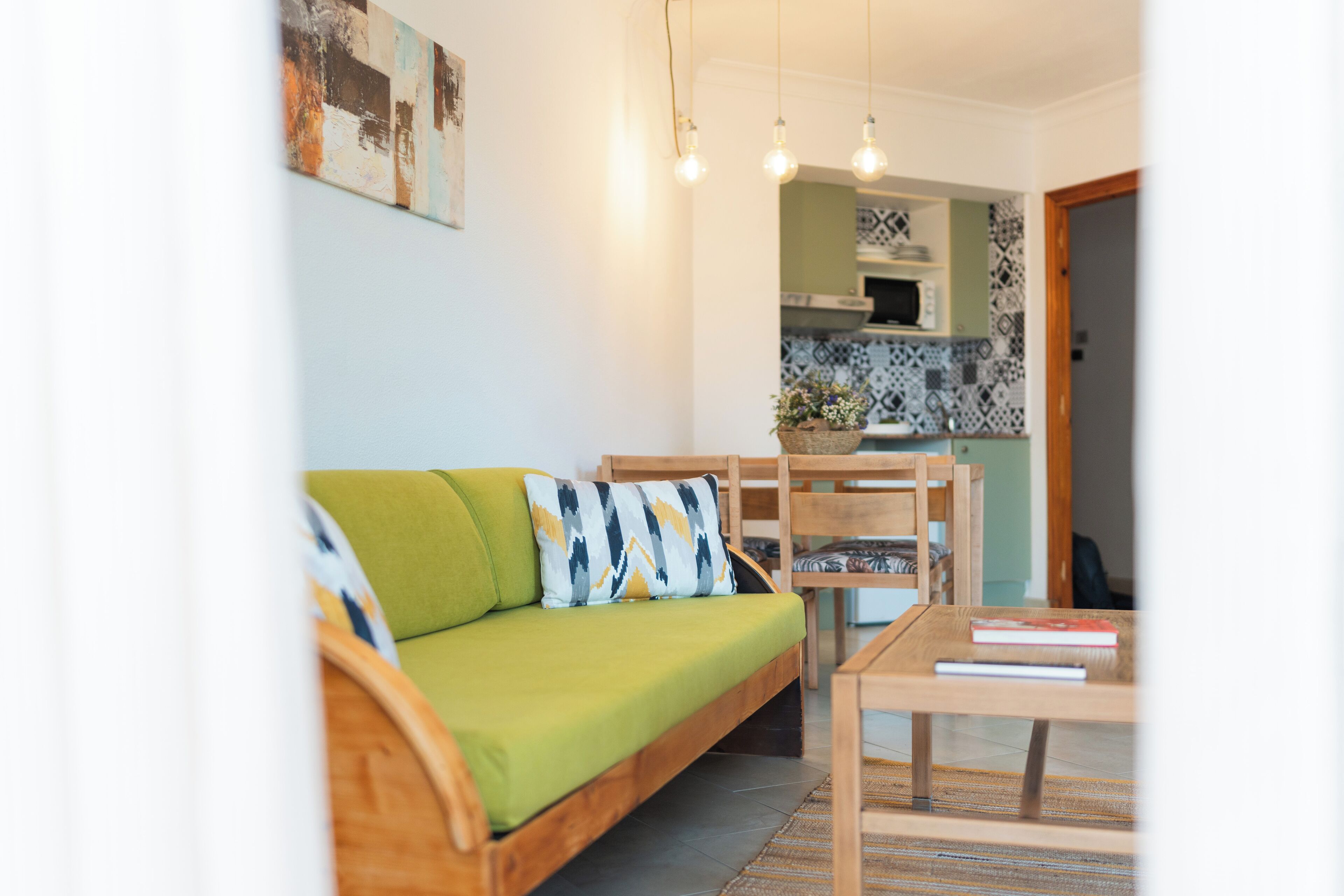 Una sala de estar con un sofá verde, una mesa de centro de madera y un comedor con sillas y una mesa.