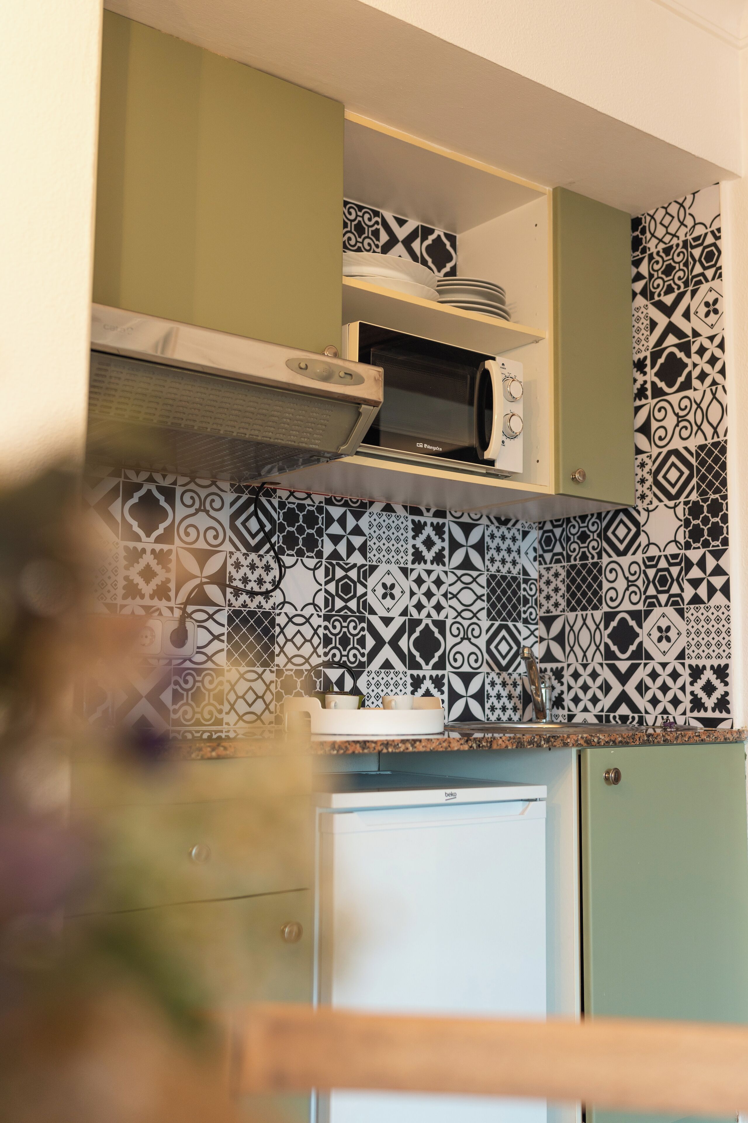 Une cuisine avec des carreaux décoratifs, un four à micro-ondes et un réfrigérateur.