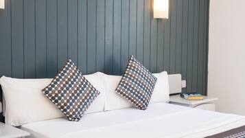 Una habitación de hotel moderna con cama, dos mesitas de noche y un espejo redondo montado en la pared.