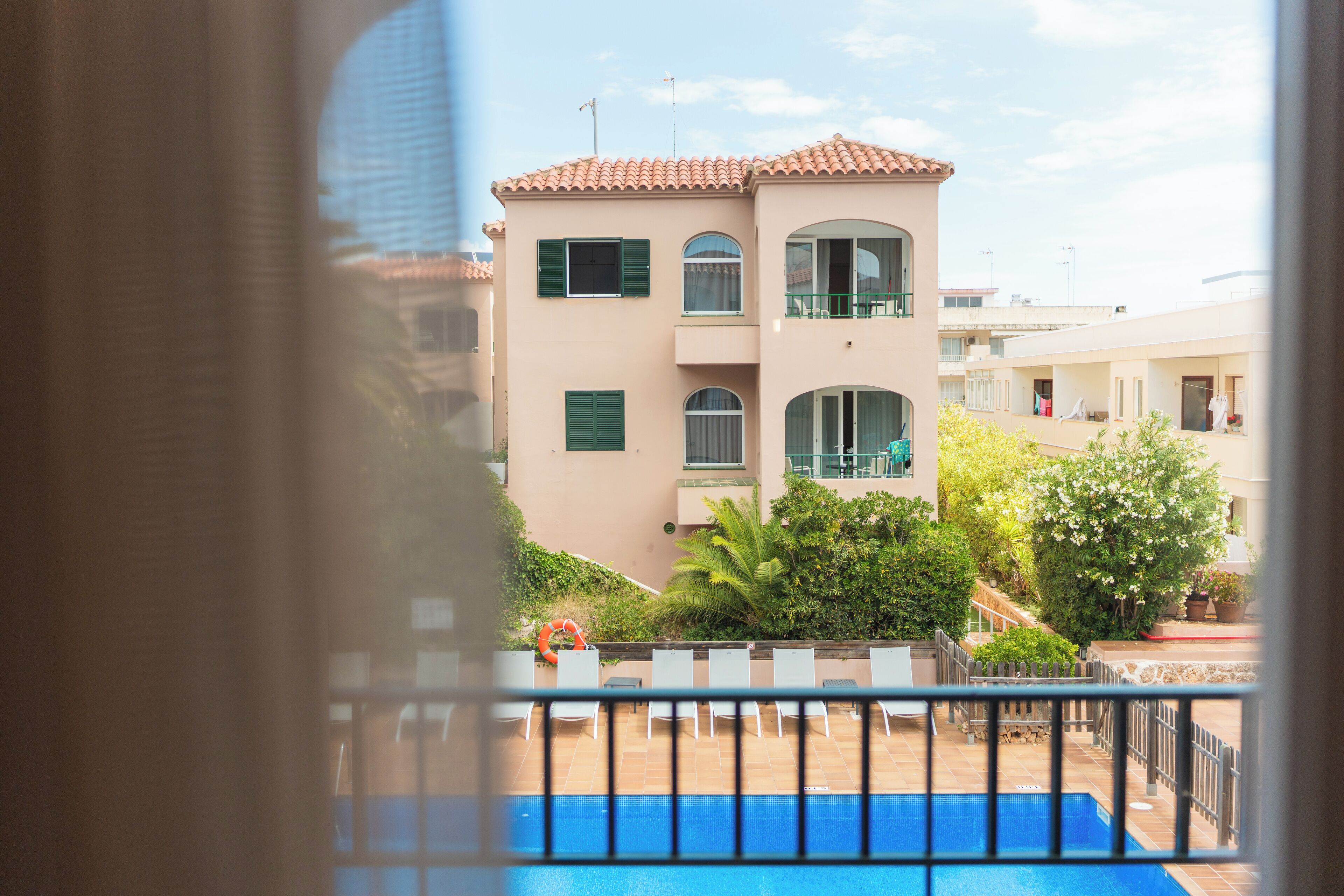 Une vue d’un immeuble doté d’une piscine, de balcons et d’un toit recouvert de tuiles.