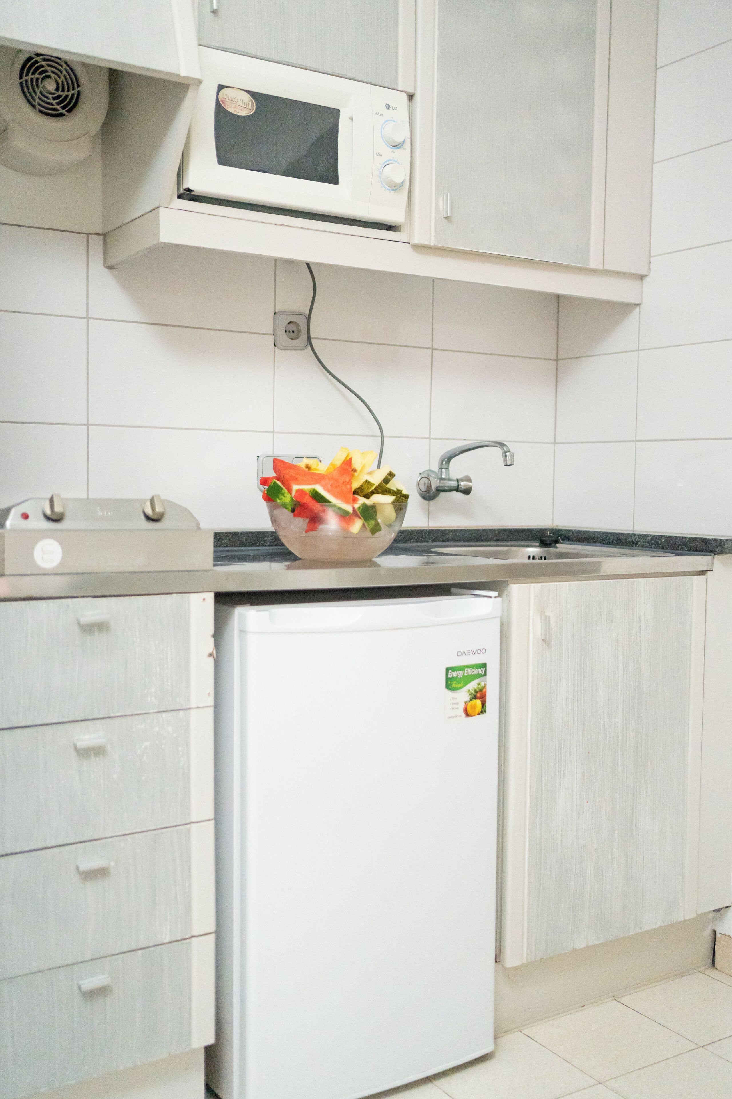 A kitchen with a microwave, a sink, a toaster, and a refrigerator.
