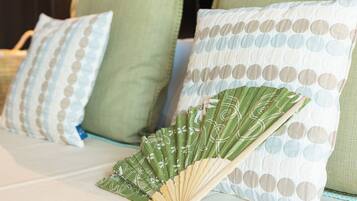 Una cama con almohadas verdes y blancas, un ventilador y un aplique de pared.