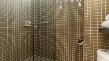 Un baño con ducha de vidrio, paredes con azulejos y un inodoro.