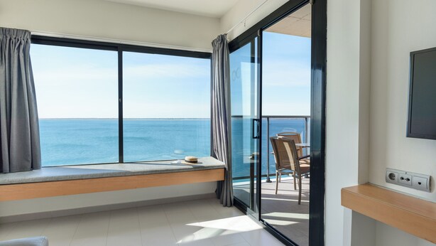 A balcony with a view of the sea, a window seat, and a table with chairs. - FERGUS Cap Roig (L'Ampolla)