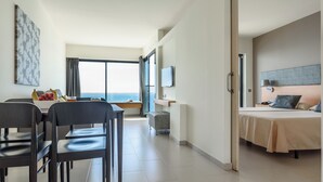 A modern hotel room with a bed, a desk, and a dining area with chairs and a table. - FERGUS Cap Roig (L'Ampolla)