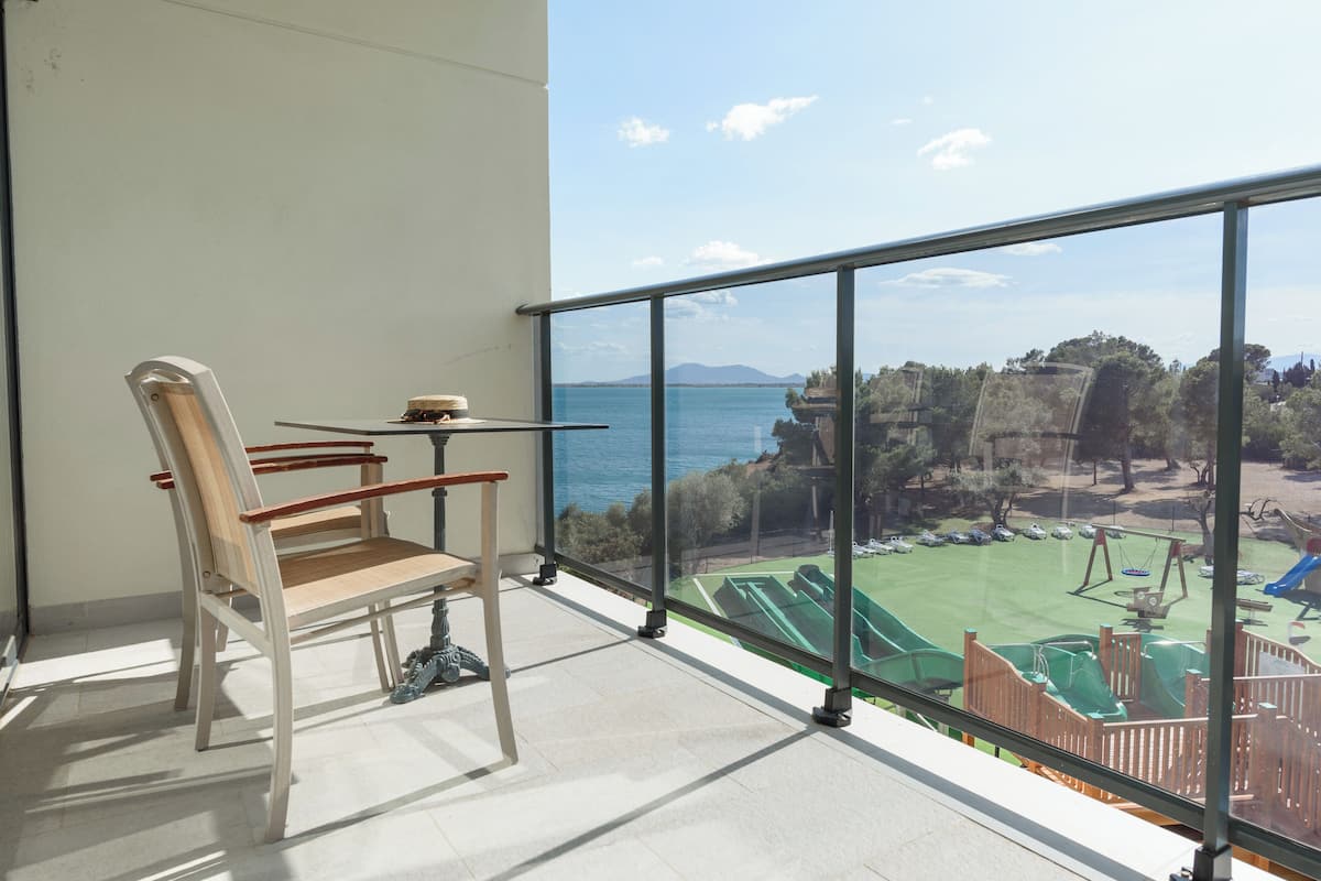 A balcony with a view of a playground and a body of water.