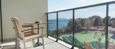 A balcony with a view of a playground and a body of water.