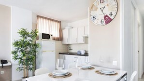 Une cuisine moderne avec des meubles blancs, un four à micro-ondes et une horloge au mur.