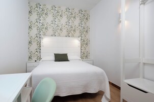 Un dormitorio con cama, mesita de noche, cómoda y escritorio.