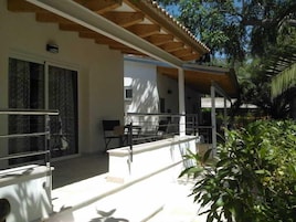 Um espaço ao ar livre coberto com corrimão, um banco e uma porta que dá para um edifício.