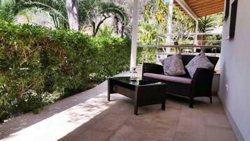 Un espace patio aménagé avec un canapé et une petite table, entouré d’une végétation luxuriante.