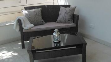 A black sofa with patterned cushions, a glass-top coffee table, and a small lantern.