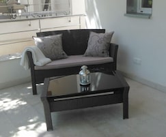 Ein schwarzes Sofa mit gemusterten Kissen, ein Couchtisch mit Glasplatte und eine kleine Laterne.