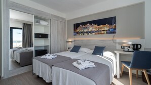 A hotel room with a bed, a desk, a chair, a wardrobe, and a painting of a marina. - Medplaya Bali (Benalmádena)