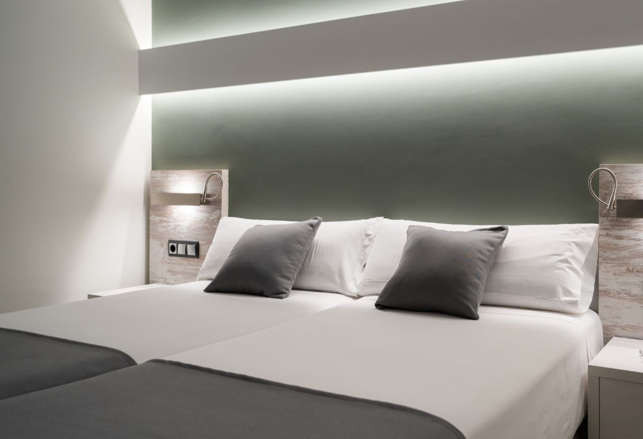 Una camera d'hotel moderna con un letto grande, due comodini e una mensola a incasso.