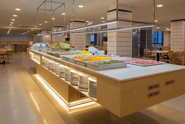 A buffet area with various food options, a seating area with tables and chairs, and a modern interior design. - Medplaya Bali (Benalmádena)