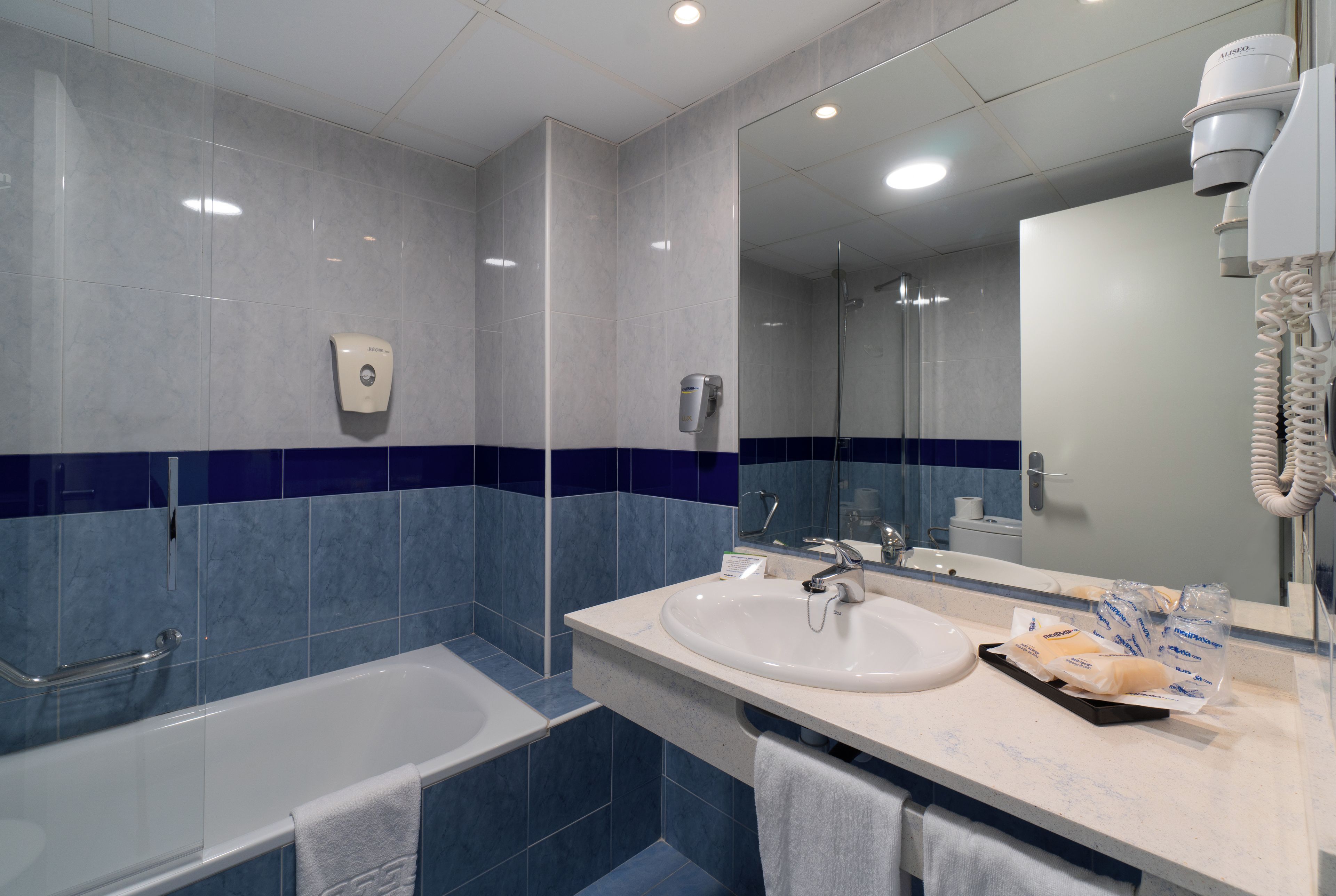 Ein Badezimmer mit Badewanne, Waschbecken, Spiegel und Handtuchhalter.