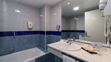 Ein Badezimmer mit Badewanne, Waschbecken, Spiegel und Handtuchhalter.