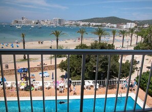 A poolside view with a beach and cityscape in the background. - Hotel Ses Savines (Sant Antoni de Portmany)