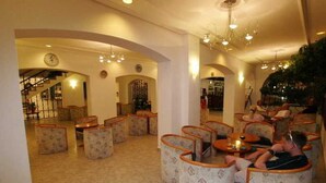 Un hall de hotel con una escalera, zona de estar y un bar.