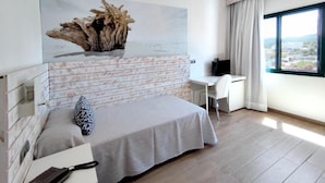 A modern bedroom with a bed, a desk, and a large window.