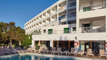 Um hotel com piscina, várias varandas e espreguiçadeiras.