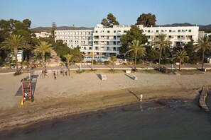 A beachfront hotel with multiple balconies, a pool area, and palm trees.