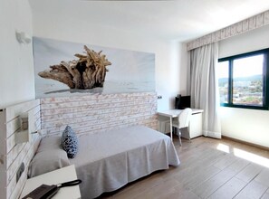 Un dormitorio moderno con cama, escritorio y un amplio ventanal.