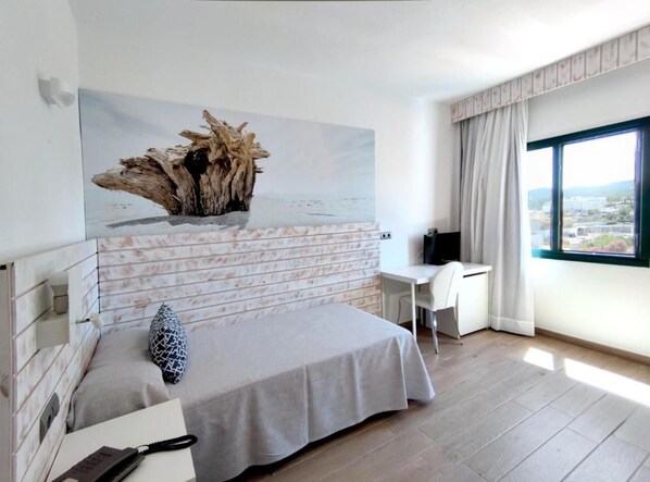 A modern bedroom with a bed, a desk, and a large window.