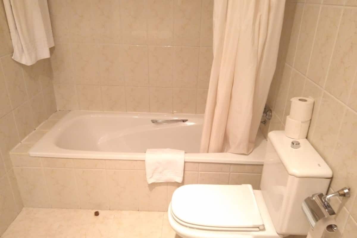 A bathroom with a bathtub, toilet, and a towel rack.