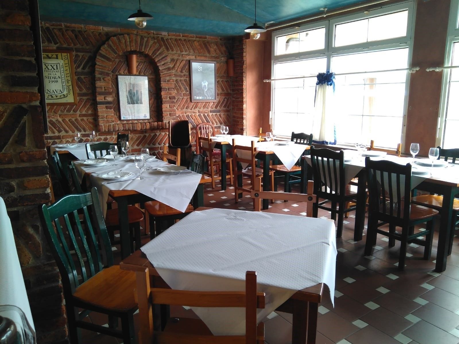 A restaurant with brick walls, wooden tables, and chairs.