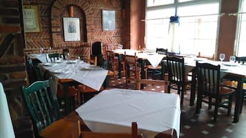 A restaurant with brick walls, wooden tables, and chairs.