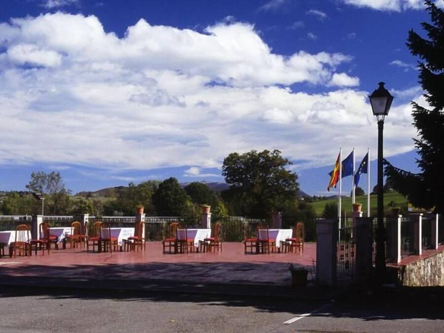 Un espacio al aire libre con mesas, sillas, banderas y un farol.