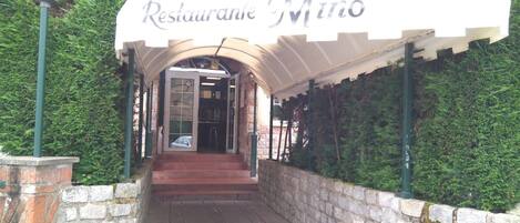 Una entrada cubierta a Casa Sidreria Restaurante Mino, con paredes de piedra y un sendero empedrado que lleva a la entrada.