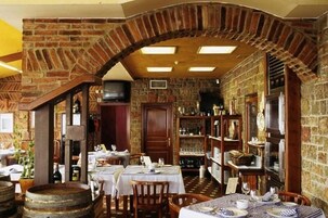Un restaurante con paredes de ladrillo, mesas de madera y piso de piedra.