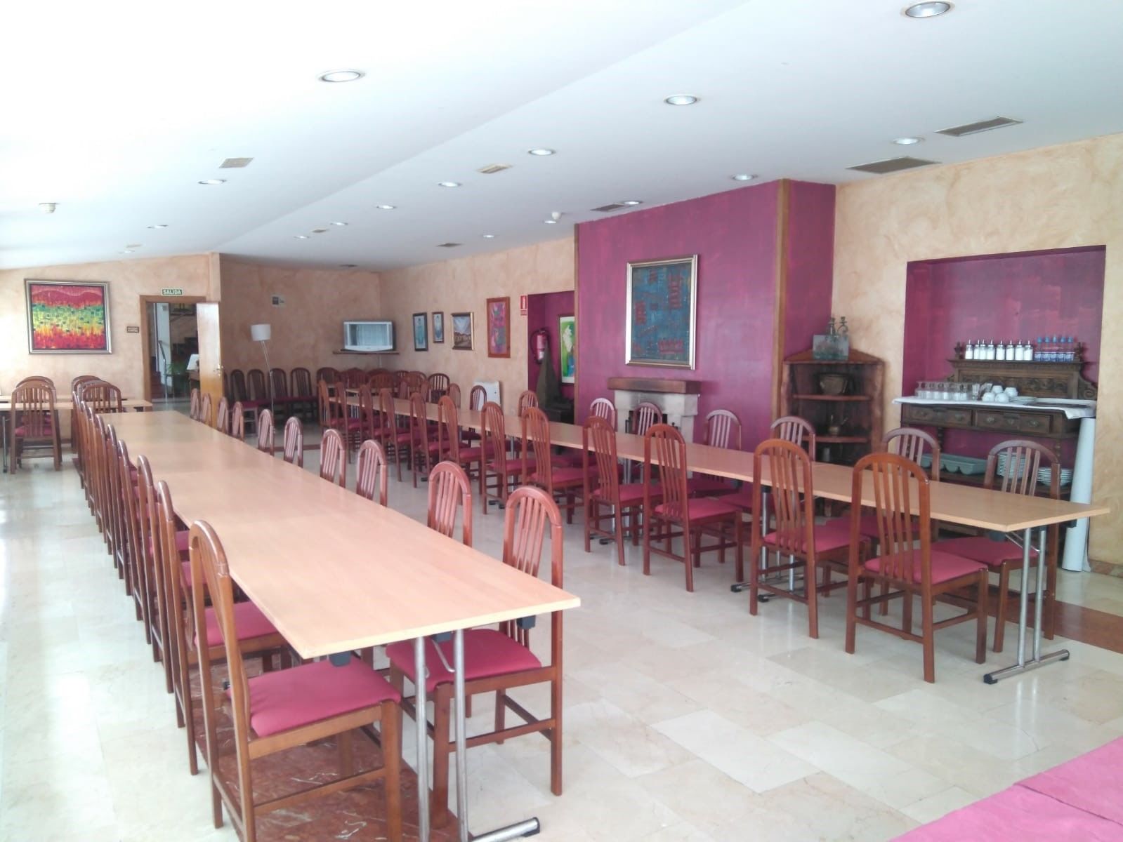 Un salón de conferencias con una larga mesa y sillas, un televisor y obras de arte en las paredes.