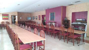 Un salón de conferencias con una larga mesa y sillas, un televisor y obras de arte en las paredes.
