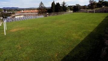 Un campo cubierto de césped con un arco de fútbol y paneles solares al fondo.
