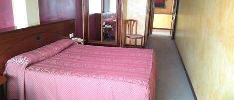 Ein Hotelzimmer mit Bett, Sessel, Schreibtisch und Spiegel.