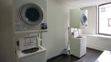 A laundry room with two washing machines and a dryer.