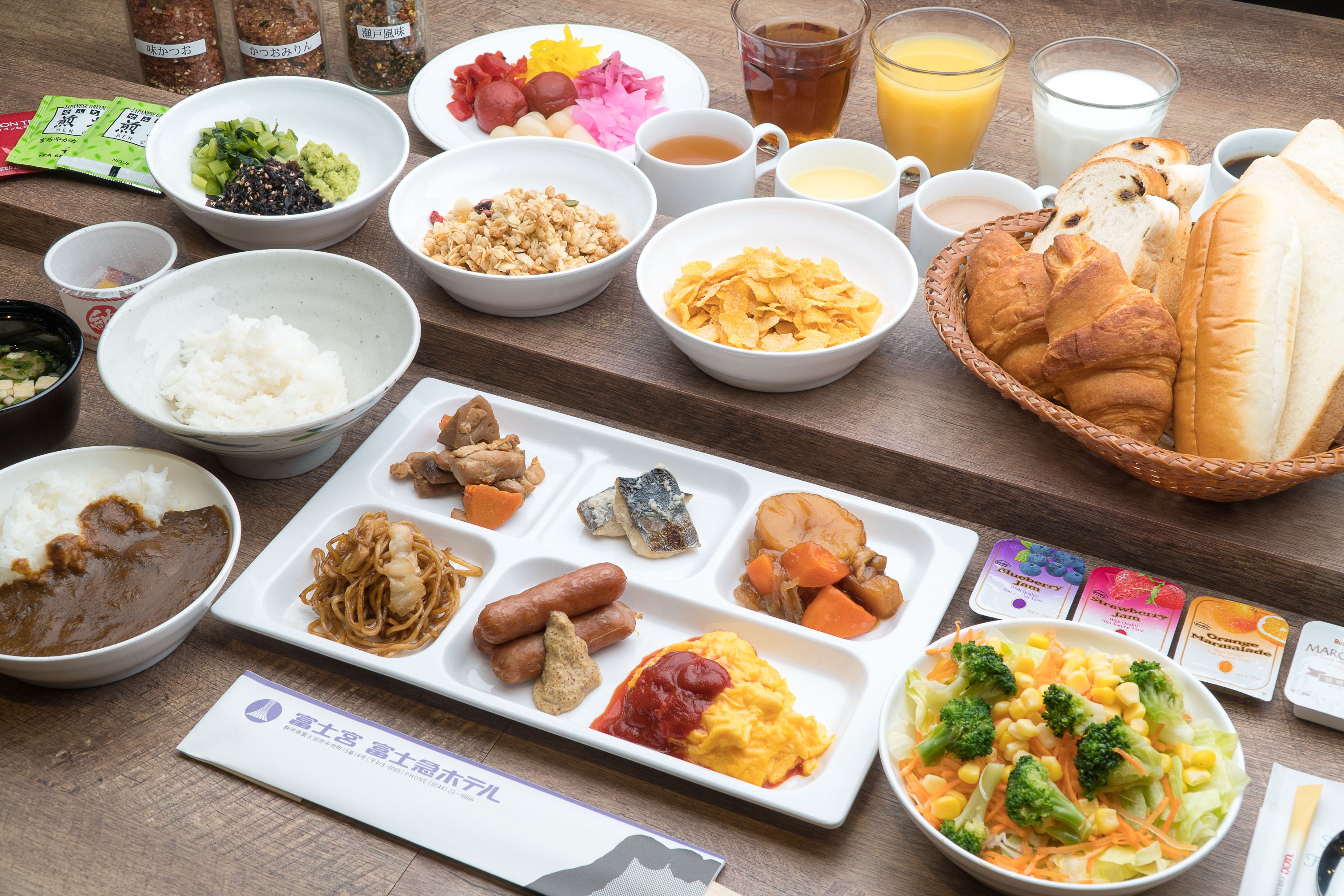A variety of dishes including rice, noodles, and vegetables, arranged on a wooden table.