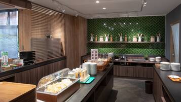 Una cocina moderna con detalles de madera, un salpicadero de azulejos verdes y diversos utensilios de cocina en estantes.