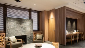 A modern interior with a round table, chairs, a fireplace, and a dining area with a wooden partition. - Fujinomiya Fujikyu Hotel (Fujinomiya)