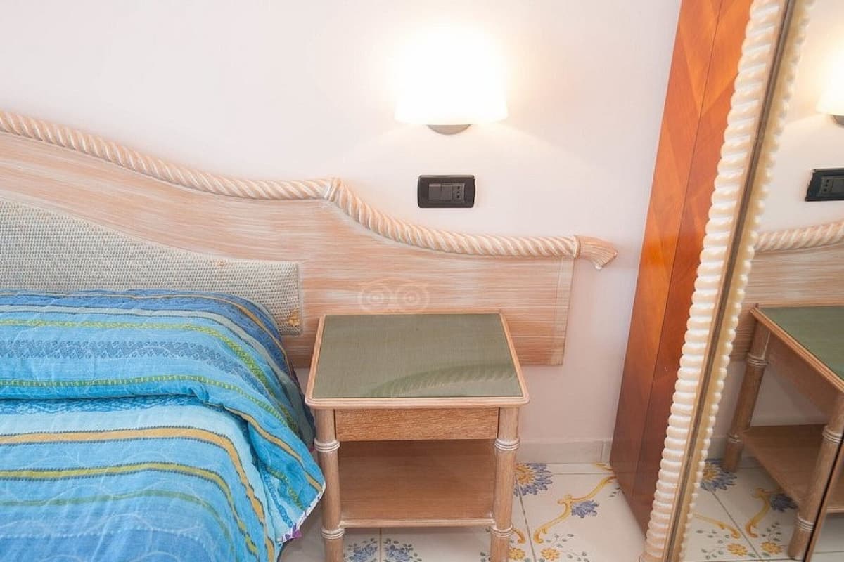 Un dormitorio con cama, mesita de noche y espejo.