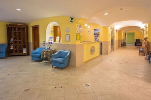 A spacious lobby with a reception desk, blue armchairs, and a tiled floor. - Hotel Terme Cristallo Palace  (Casamicciola Terme)