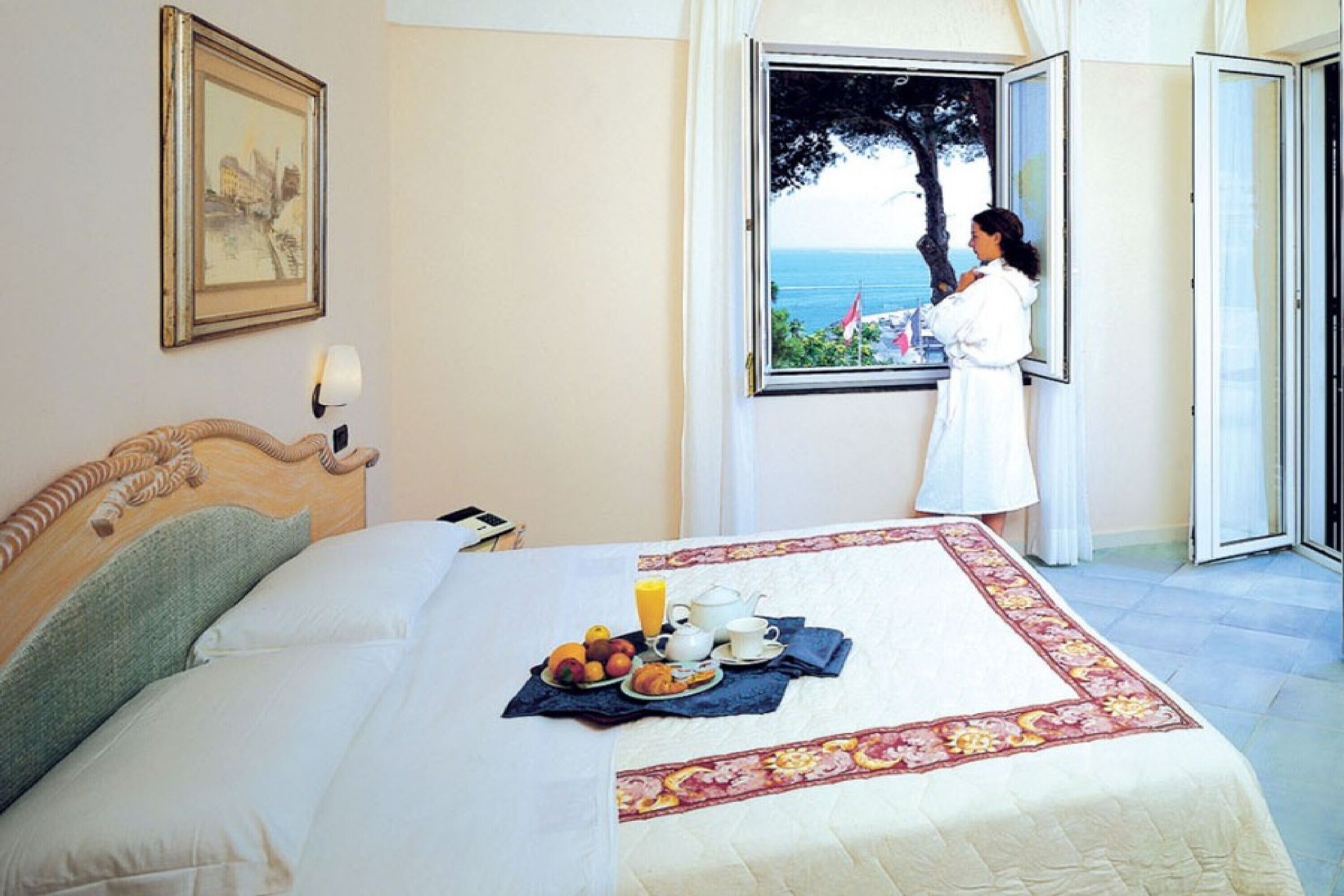 Un dormitorio con cama, bandeja de desayuno y ventana con vista al mar.