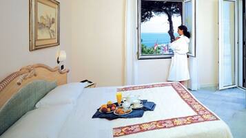 Un dormitorio con cama, bandeja de desayuno y ventana con vista al mar.